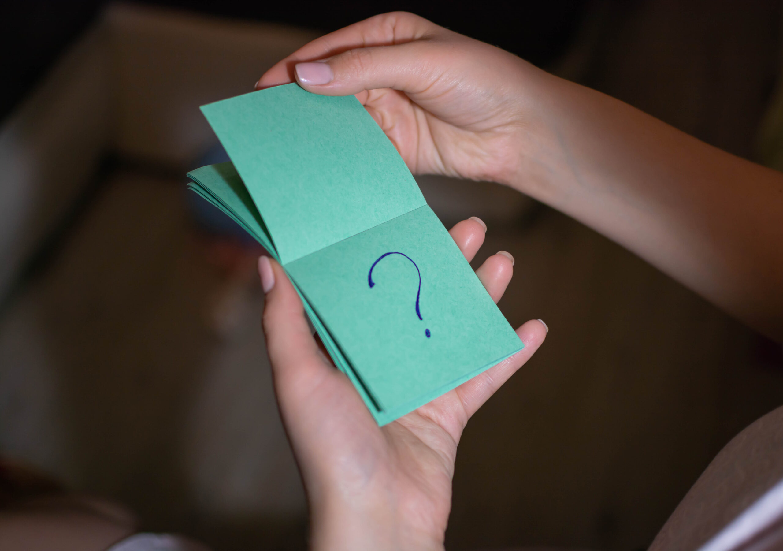 Girl looks at a piece of paper with a question mark on a green background