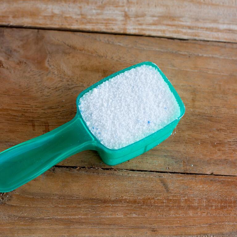 Detergent powder, detergent washing powder in the measuring spoon on wood background